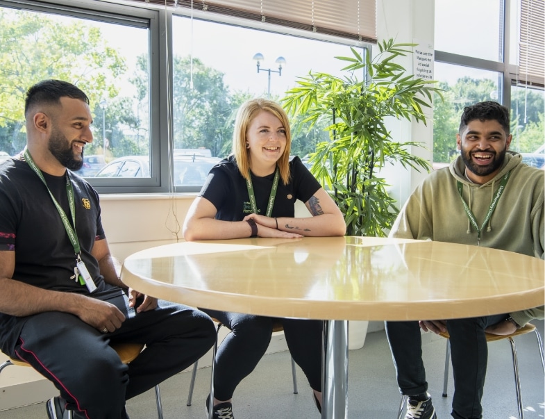 A team of three colleagues laughing around a table